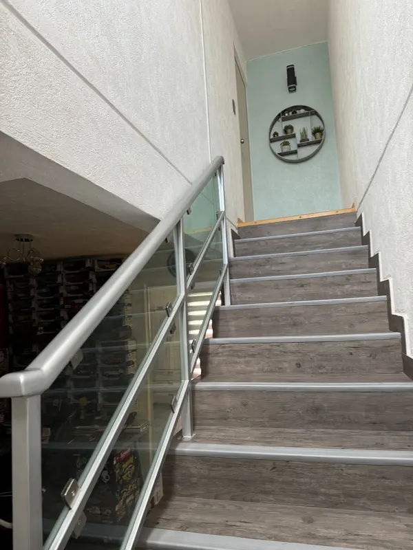 Escalera con piso vinílico y barandal de cristal templado
